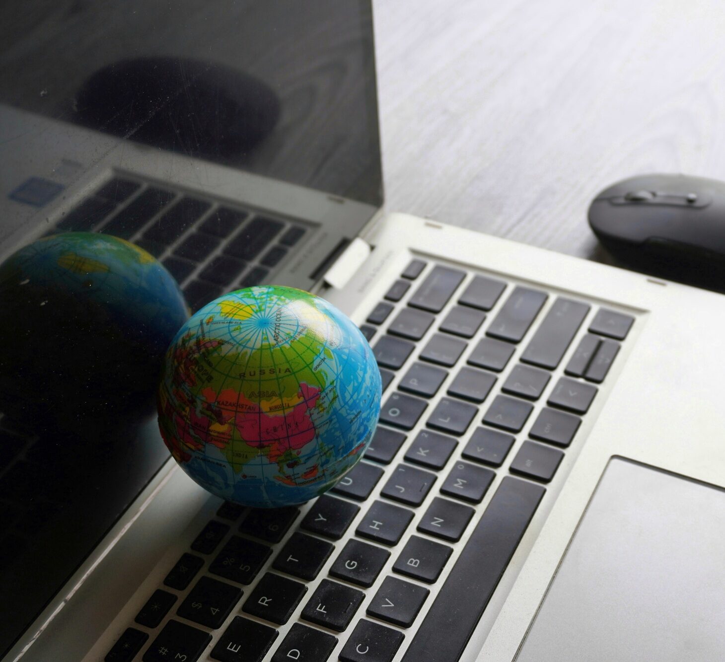 Close up image of globe, laptop keyboard and computer mouse.